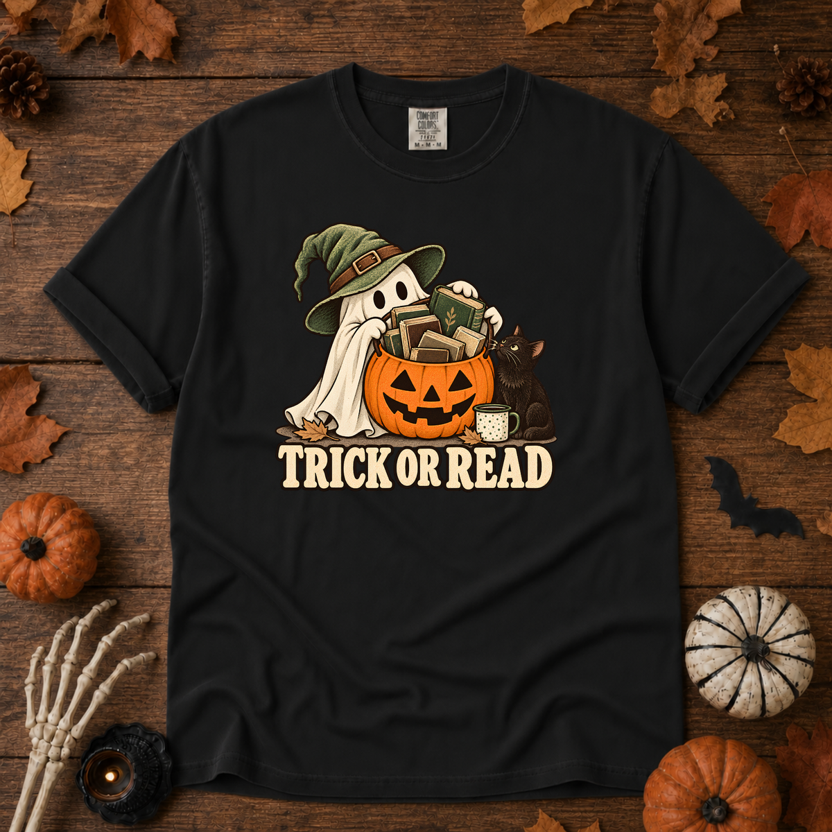 Trick or Read Halloween book lover t-shirt in Black - ghost in a witch hat with a pumpkin bucket full of books and a black cat, on garment-dyed Comfort Colors cotton