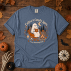 Blue Jean Comfort Colors t-shirt featuring a ghost sitting in a pumpkin chair with a steaming mug of cocoa, campfire, lantern, mushrooms and maple leaves, Trail & Ember Co.