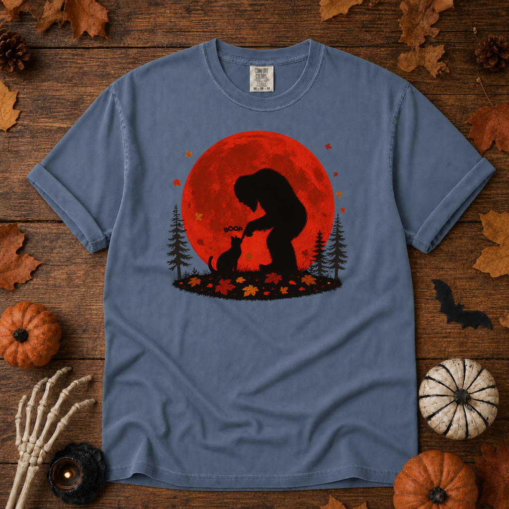 Blue Jean Comfort Colors t-shirt featuring Bigfoot booping a black cat's nose in front of a red autumn moon, with maple leaves and pine trees, Trail & Ember Co.