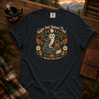 Graphite Comfort Colors t-shirt featuring a vintage Night Owl Nature Club badge design — barn owl perched on a field guide book beside a jack-o'-lantern lantern, moon phases, compass, pinecones, bats, and autumn leaves, Trail & Ember Co.