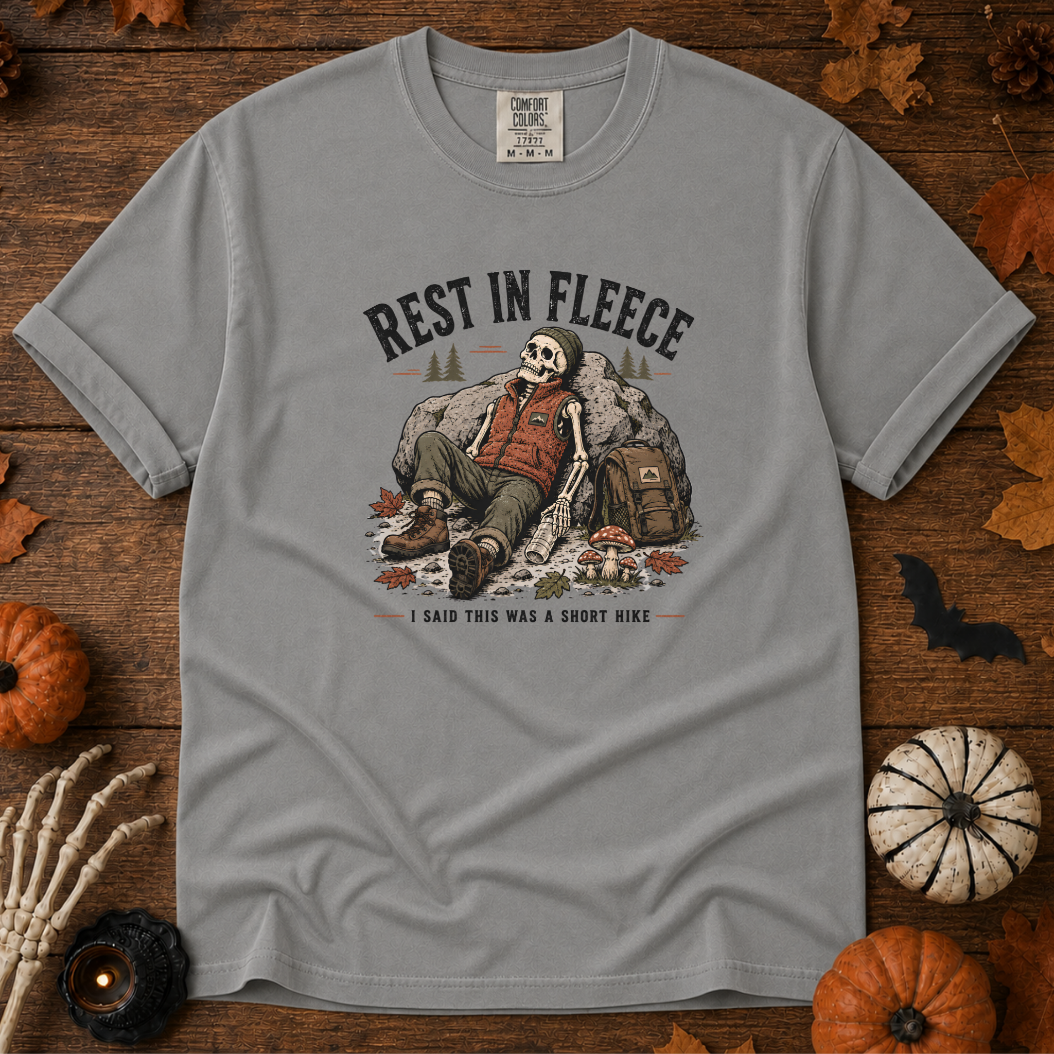 Grey Comfort Colors t-shirt featuring a skeleton wrapped head to rib in fleece, propped against a lantern, Trail & Ember Co.