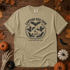 Khaki Comfort Colors t-shirt featuring a lantern glowing on a switchback trail under the moon, Trail & Ember Co.