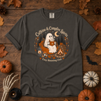 Pepper Comfort Colors t-shirt featuring a ghost sitting in a pumpkin chair with a steaming mug of cocoa, campfire, lantern, mushrooms and maple leaves, Trail & Ember Co.