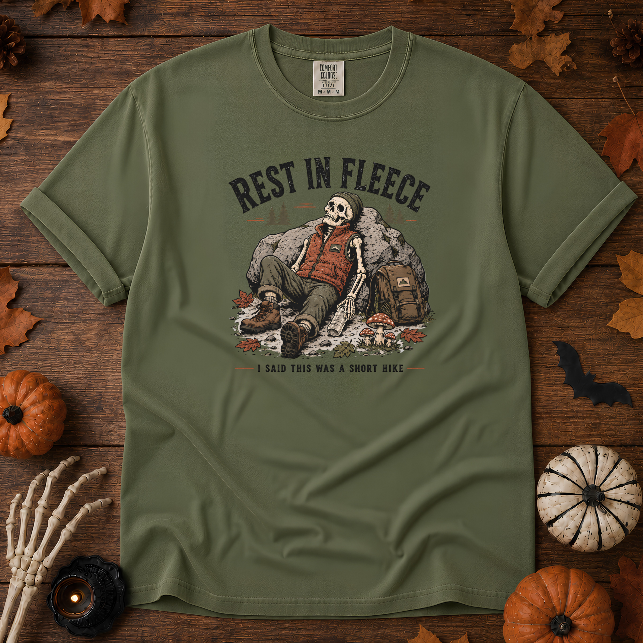 Sage Comfort Colors t-shirt featuring a skeleton wrapped head to rib in fleece, propped against a lantern, Trail & Ember Co.
