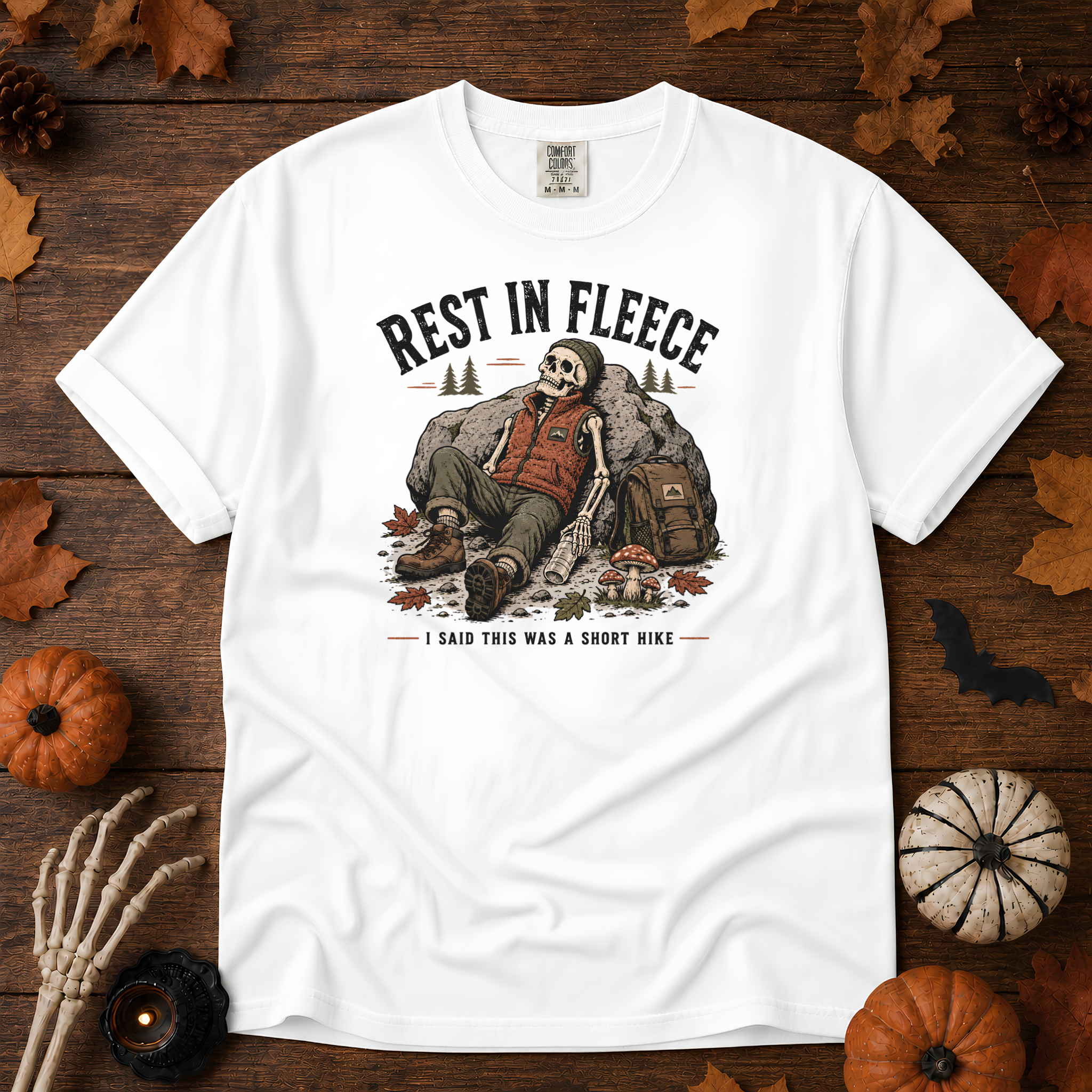 White Comfort Colors t-shirt featuring a skeleton wrapped head to rib in fleece, propped against a lantern, Trail & Ember Co.