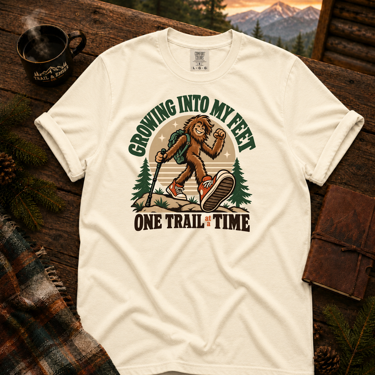 Ivory Comfort Colors T-shirt with Teen Bigfoot hiking in orange sneakers with Growing Into My Feet lettering.