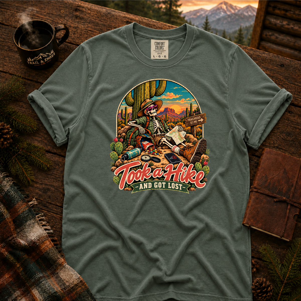Blue Spruce Comfort Colors T-shirt with Took a Hike and Got Lost skeleton resting beside a cactus with a map.